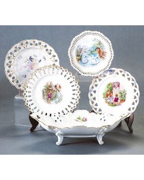 2003-Lote en porcelana esmaltada centroeuropea formado por cuatro bandejitas circulares con ala calada y campo decorado con flores y personajes y cestita del mismo estilo.