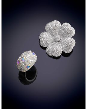 1002-SWAROVSKI CONJUNTO FORMADO POR SORTIJA BOMBÉ Y BROCHE EN FORMA DE FLOR CON MONTURA BAÑANA EN RODIO.