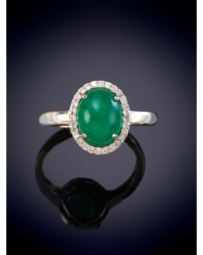 6-ELEGANTE SORTIJA CON UN CABUJÓN CENTRAL DE ESMERALDA ORLADO POR BRILLANTES sobre una montura en oro blanco de 18K. 