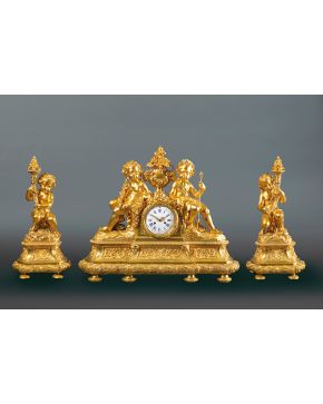 783-Reloj con guarnición de candelabros en forma de torcheros Francia, S.XIX, Reloj con numeración romana decorado con niños de bulto redondo y remate de florero. Mecanismo de cuerda llave.  Medida
