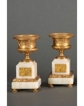 981-Pareja de copas Medici, Francia, s. XIX. Decoración de amorcillos sobre peana de mármol blanco con escena clásica. Altura: 23 cm.