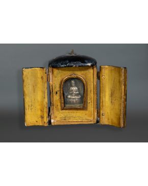 2418-Pequeña capilla antigua en madera lacada en negro por fuera y dorada por dentro que cobija una pequeña figura de Buda en metal plateado.  Longitu