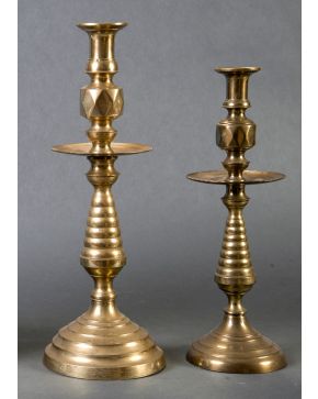 331-Lote formado por dos candeleros en bronce de diferente tamaño siguiendo el mismo modelo decorativo. Base circular escalonada, fuste lobu
