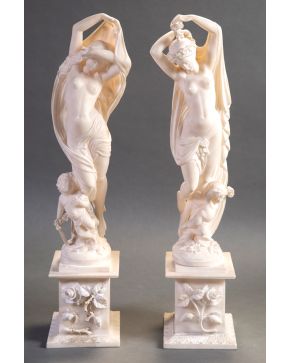 306-Lote formado por dos esculturas de bulto redondo en mármol blanco sobre peanas con decoración floral, representando figuras femeninas si