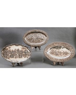 321-Lote de tres platos españoles en plateado con escenas historicistas y perfiles decorados con tornapuntas, medallones y elementos vegetal