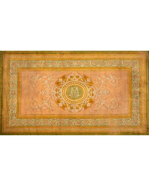 328-Alfombra en lana de nudo español estilo Carlos IV. Cartela en tonos dorados y blancos sobre campo rosa con cenefa de