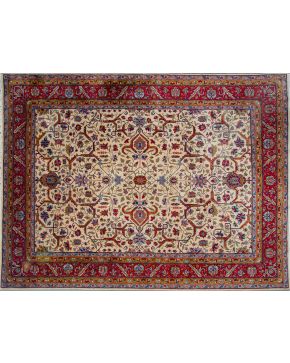 1012-Gran alfombra persa en lana, s. XX. Campo beige y motivos vegetales y florales esquematizados en tonos verde y granate combinados.  Medidas: 400 