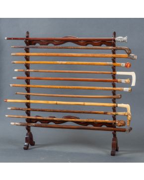 371-Colección de doce bastones con bastonero en madera, con mangos en plata, dorado, madreperla, hueso, madera tallada y piedras. Altura bastonero: 86