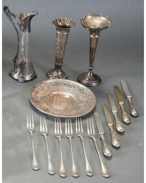 1008-Lote Art Nouveau en plata punzonada compuesto por dos violeteros, una jarrita, cinco cuchillos, seis tenedores y un plato de exquisita decoración