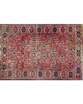 1005-Alfombra persa en lana con decoración geométrica en campo sobre fondo granate.  Medidas: 310 x 211 cm. 