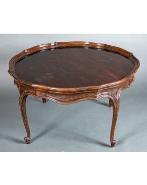 384-Mesa de centro circular, s. XIX, en madera tallada de nogal con perfil mixtilíneo sobre patas cabriolé y pies de vol