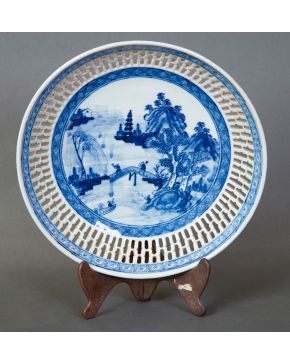 55-Decorativo plato en porcelana china azul y blanca con campo con representación de paisaje y alero