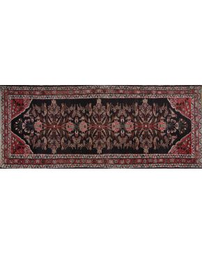27-Alfombra oriental de pasillo en lana con motivos florales sobre campo negro y borde principal en 