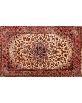502-Alfombra oriental en tonos beige y rojos con medallón central en azul y bordura perimetral con decoración de flores y hojas. 