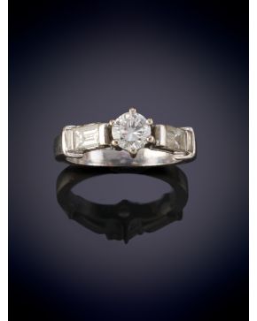 19-ELEGANTE SORTIJA CON UN BRILLANTE CENTRAL FLANQUEADO POR DIAMANTES EN BAGUETTE. Montura en oro blanco 18k.