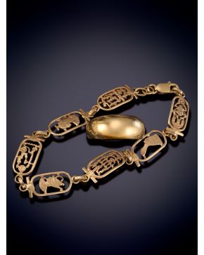58-LOTE FORMADO POR ALIANZA ANCHA Y PULSERA DE SIMBOLOS EGIPCIOS SOBRE UNA MONTURA DE ORO AMARILLO DE 18K. 