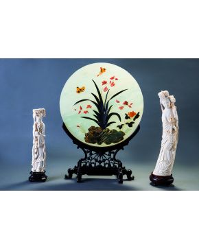 1267-Decorativo plato en jade con aplicaciones de piedras duras formando un bello motivo floral con mariposas. Sobre peana de madera. 